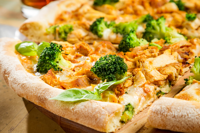 Closeup of fresh pizza with broccoli, chicken and cheese